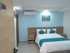 Un dormitorio con una cama, una mesita de noche, un aire acondicionado de pared y un cuadro.