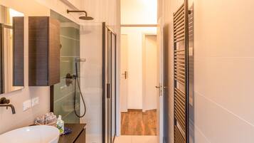 Un bagno moderno con cabina doccia in vetro, un mobile bagno in legno e uno specchio grande.