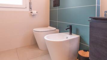 Une salle de bain équipée de toilettes, d’un lavabo et d’une poubelle.