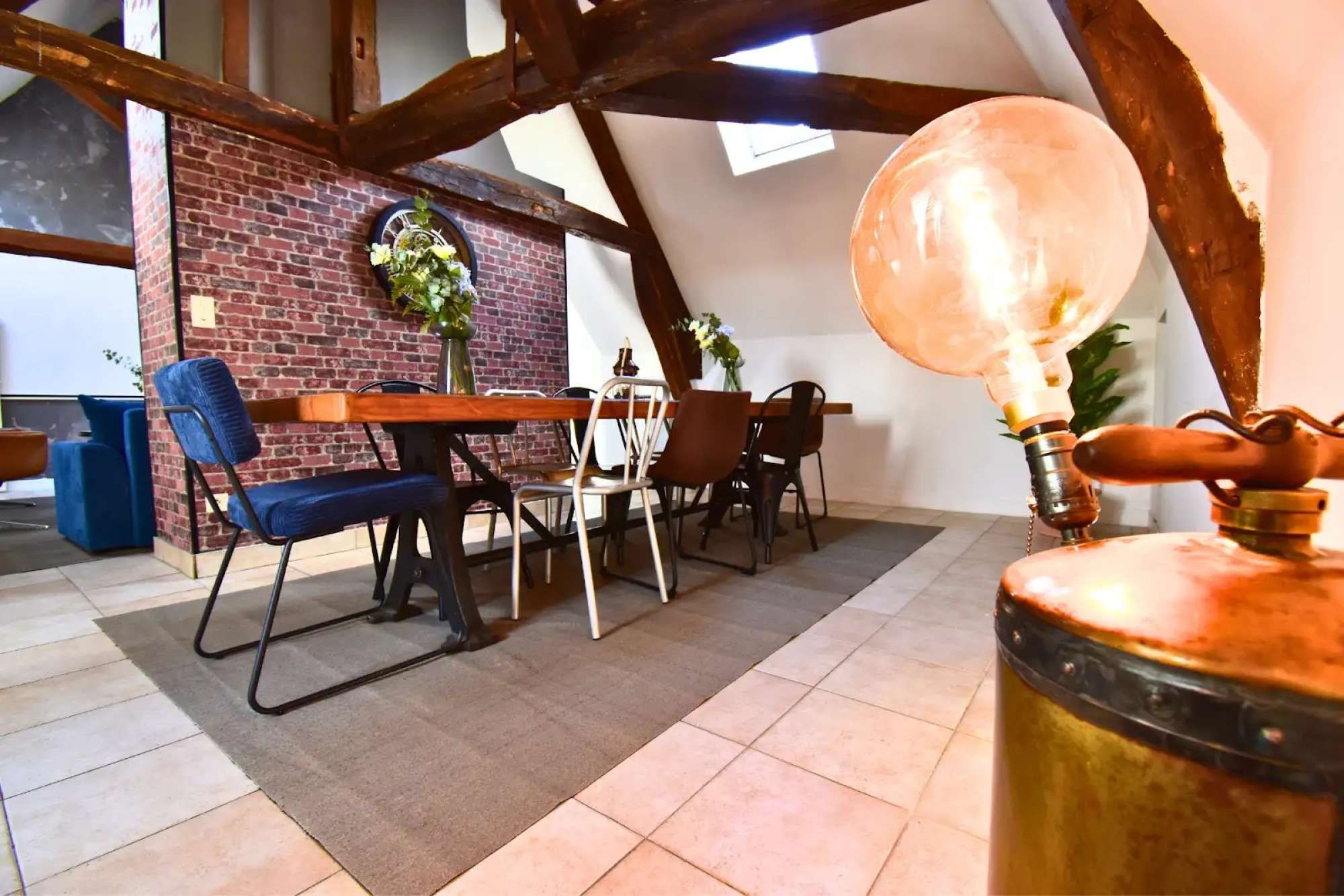 Een eetruimte met een bakstenen muur, houten balken en een tafel met stoelen.
