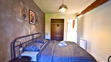 Een slaapkamer met een bed, nachtkastje, kledingkast en hanglamp.
