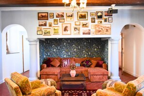 A room with a patterned wall, a sofa set, and framed pictures on the wall. - Le Haras Royal — Château de Ravenel (Ravenel)