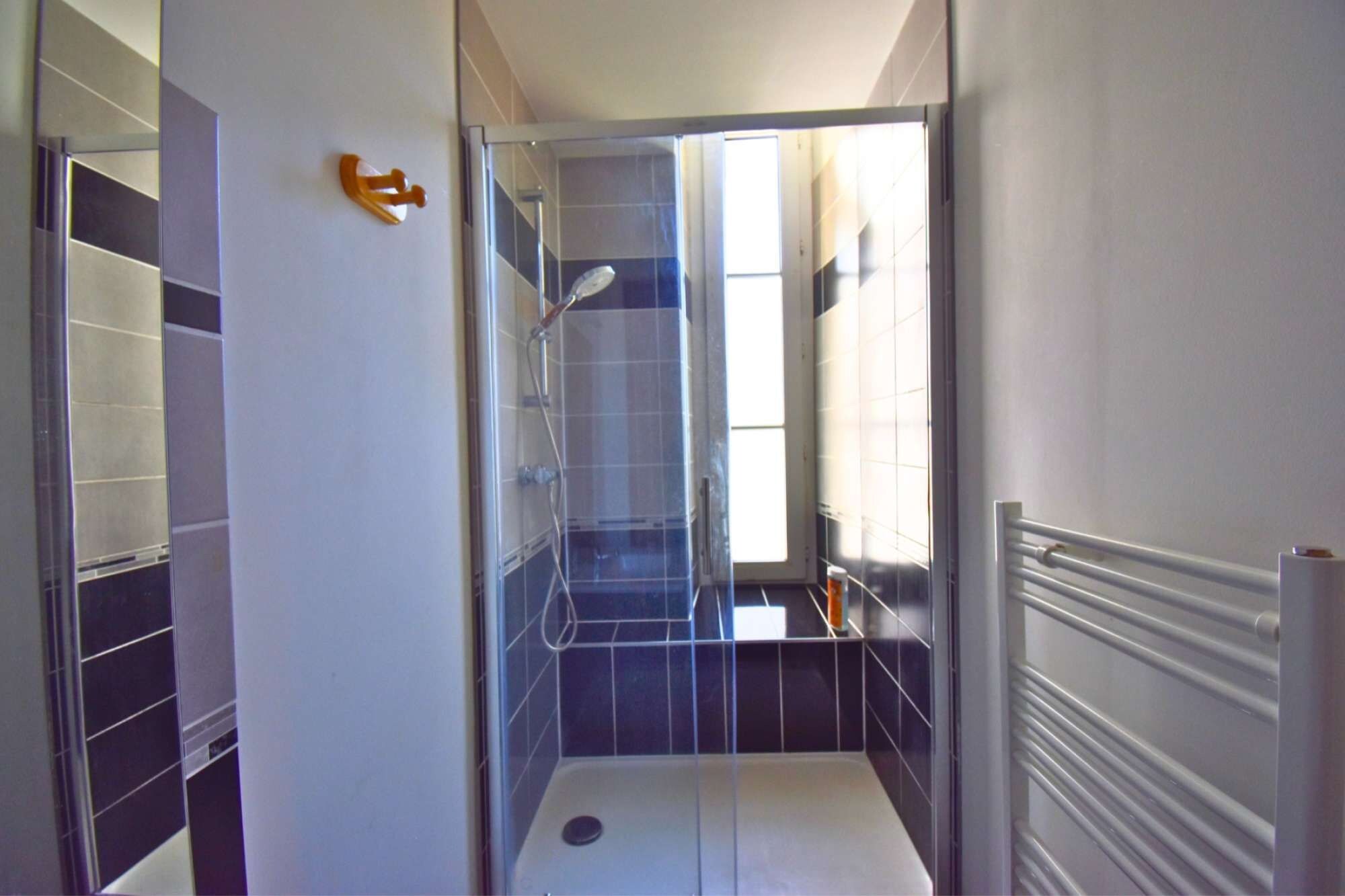 Een badkamer met een douchecabine van glas, een toilet en een handdoekhouder.