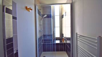 Een badkamer met een douchecabine van glas, een toilet en een handdoekhouder.
