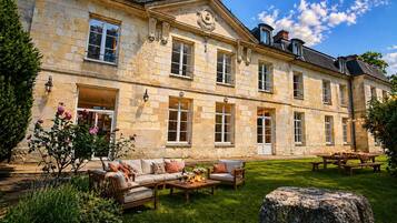 A stone building with a garden patio, outdoor seating, and a stone wall.