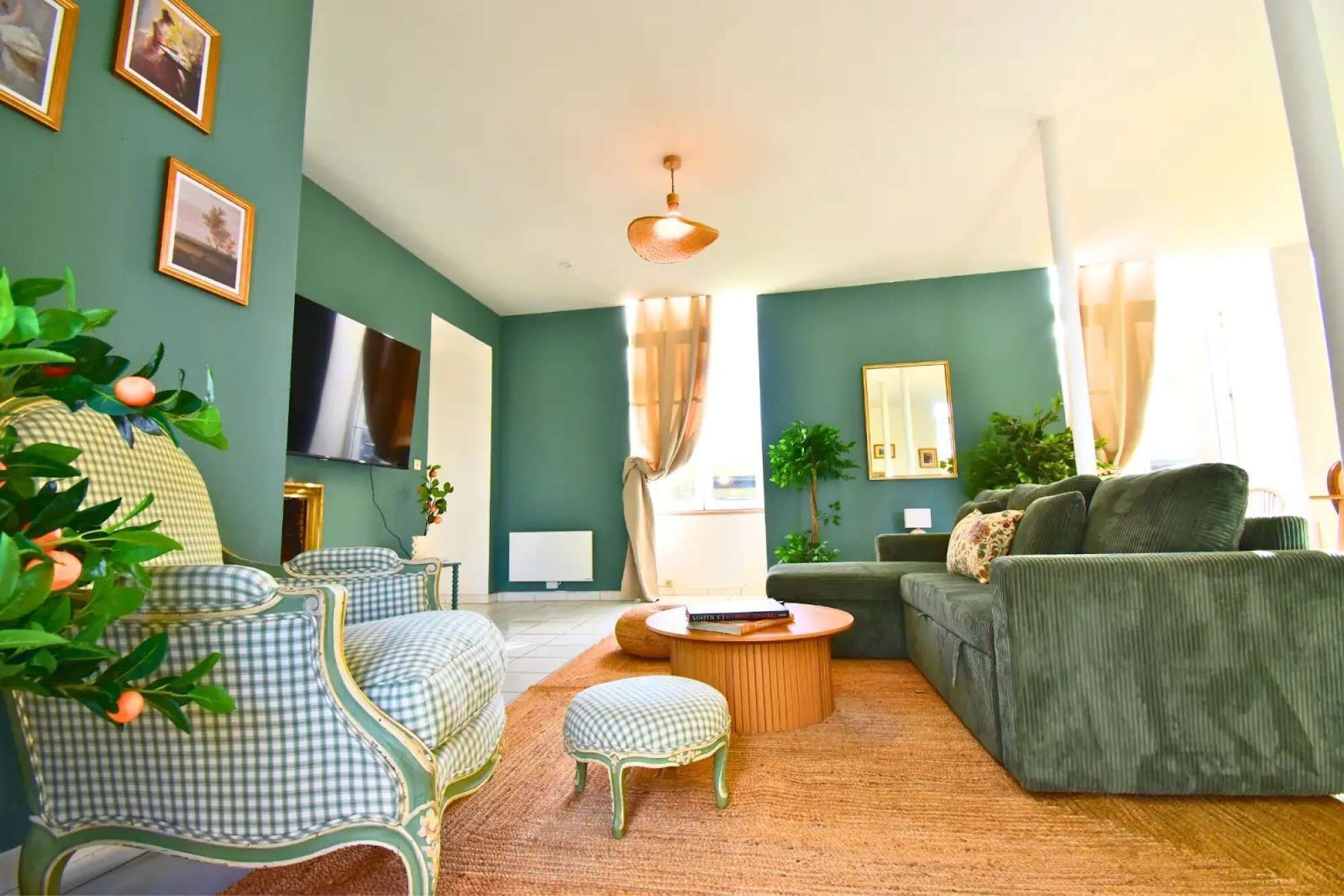 A living room with a sofa, armchair, ottoman, and a television.