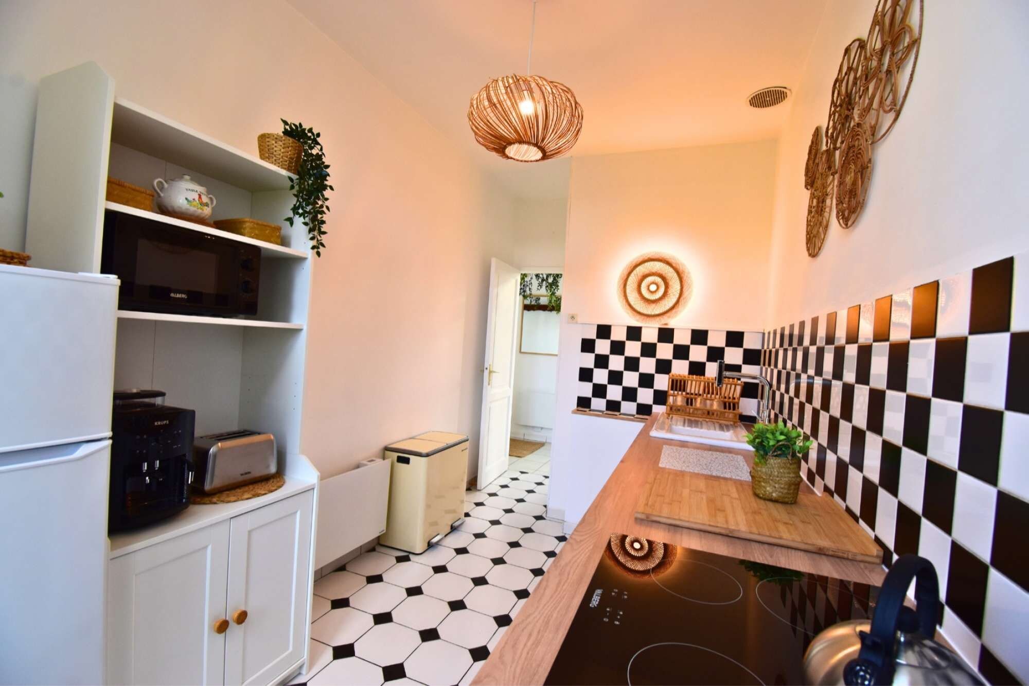 Une cuisine avec un dosseret à carreaux, une cuisinière moderne et un luminaire suspendu.