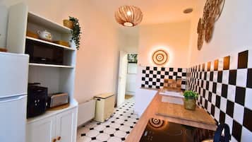 Une cuisine avec un dosseret à carreaux, une cuisinière moderne et un luminaire suspendu.