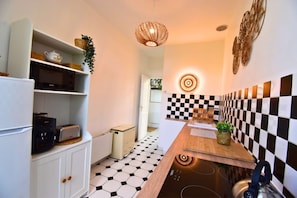Een keuken met een zwart-wit geruit spatwand, een moderne kookplaat en een hanglamp.