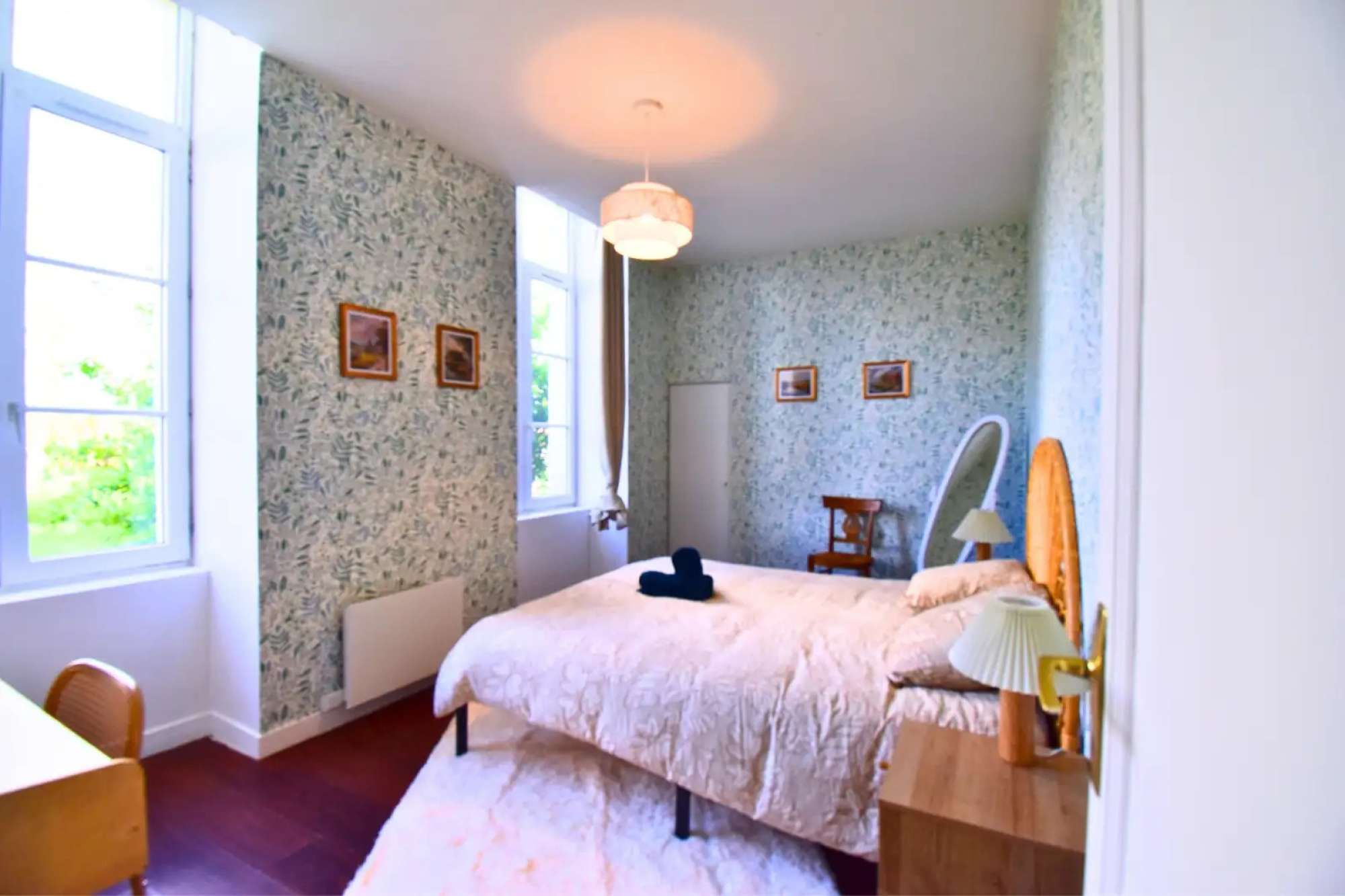 Een slaapkamer met een bed, een stoel, een bureau en een raam.