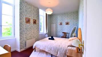 Een slaapkamer met een bed, een stoel, een bureau en een raam.