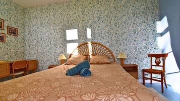 Een slaapkamer met een bed, twee nachtkastjes, een stoel en een raam.