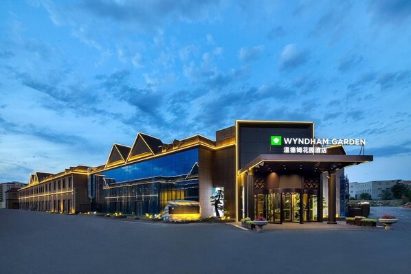 Un hotel con fachada moderna, una entrada destacada y un letrero que indica que es el Wyndham Garden.