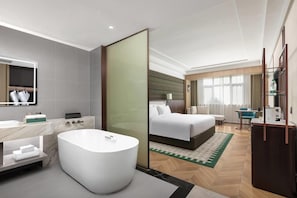 Een moderne hotelkamer met een groot bad, een afzonderlijke slaapkamer met een bed, een bureau en een stoel.
