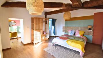 Une chambre à coucher avec un lit, une armoire en bois, un luminaire suspendu et une fenêtre avec des rideaux.