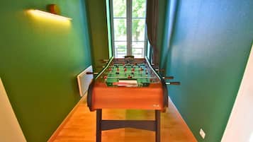 Een tafelvoetbaltafel in een smalle gang met groene wanden en een houten vloer.