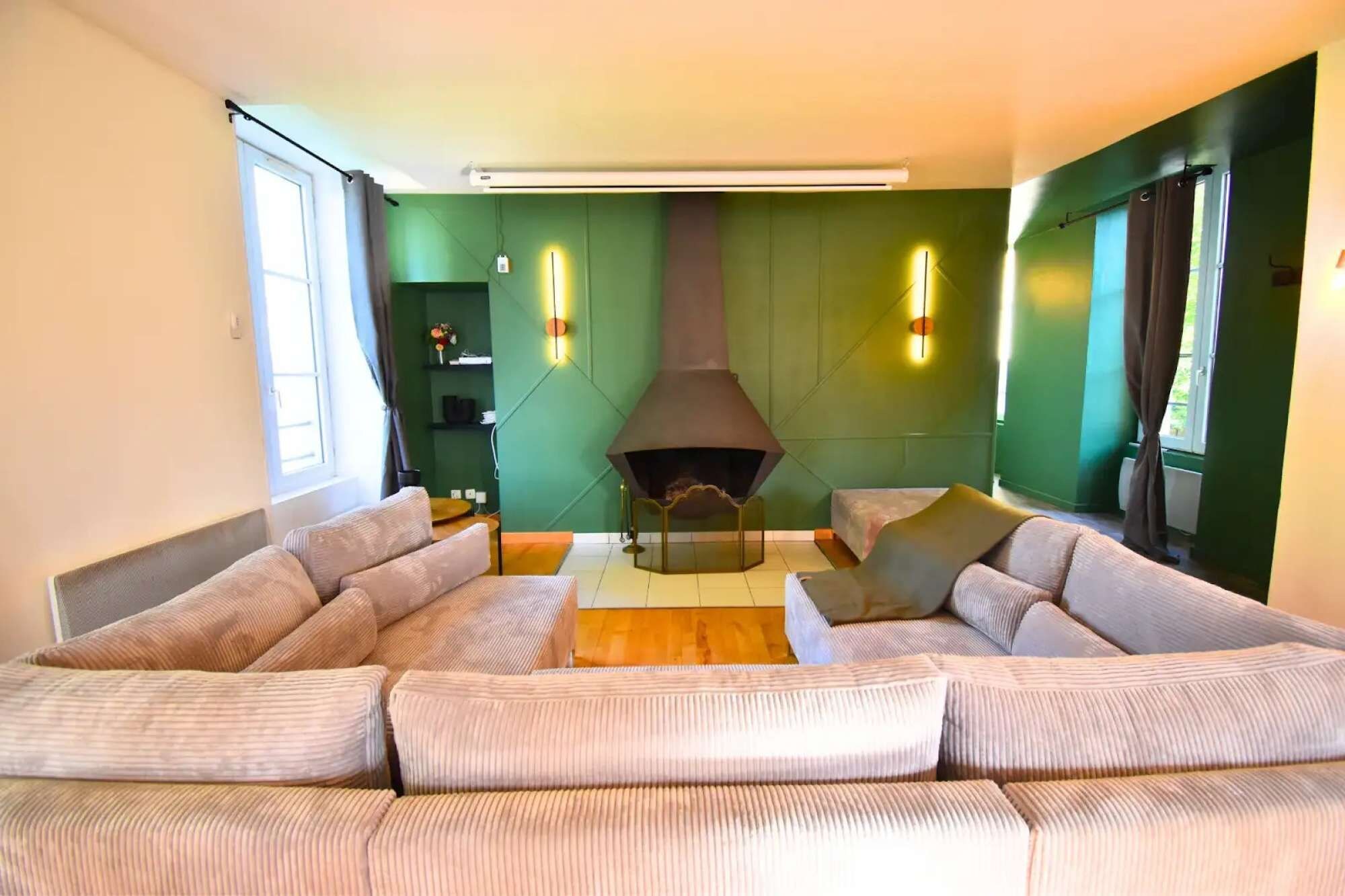 Een moderne woonkamer met een modulaire bank, een open haard en groene wanden.