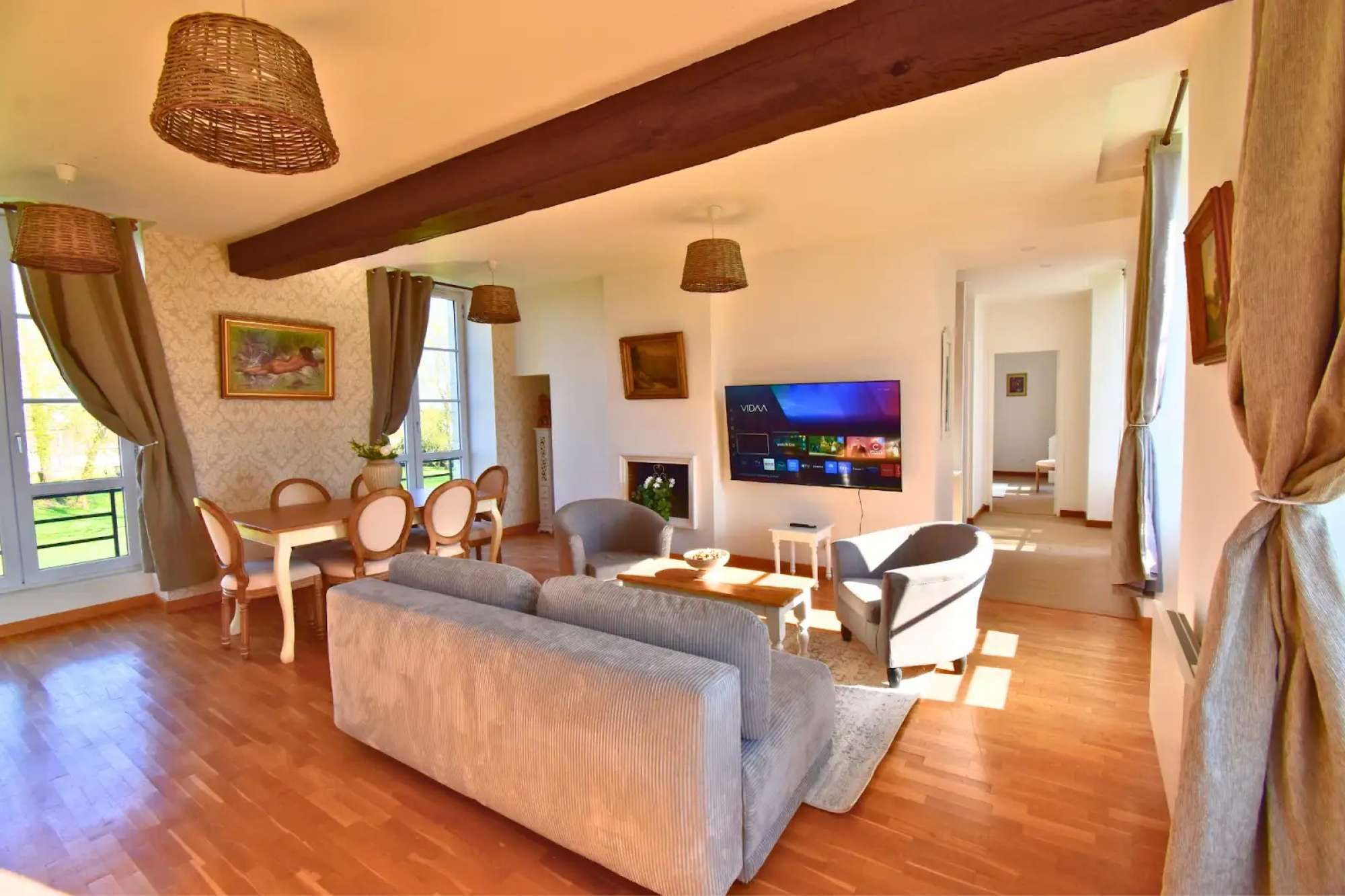 Een woonkamer met een bank, eettafel, stoelen, een televisie en een open haard.