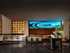 A modern lobby with a bar area, seating, and a large digital display. - Novotel Zibo New Hongcheng (Zibo)