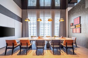 A modern conference room with a large table, chairs, and pendant lighting. - Novotel Zibo New Hongcheng (Zibo)
