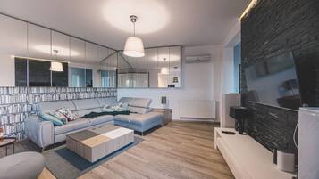 A modern living room with a sectional sofa, a coffee table, a TV, and a fireplace.
