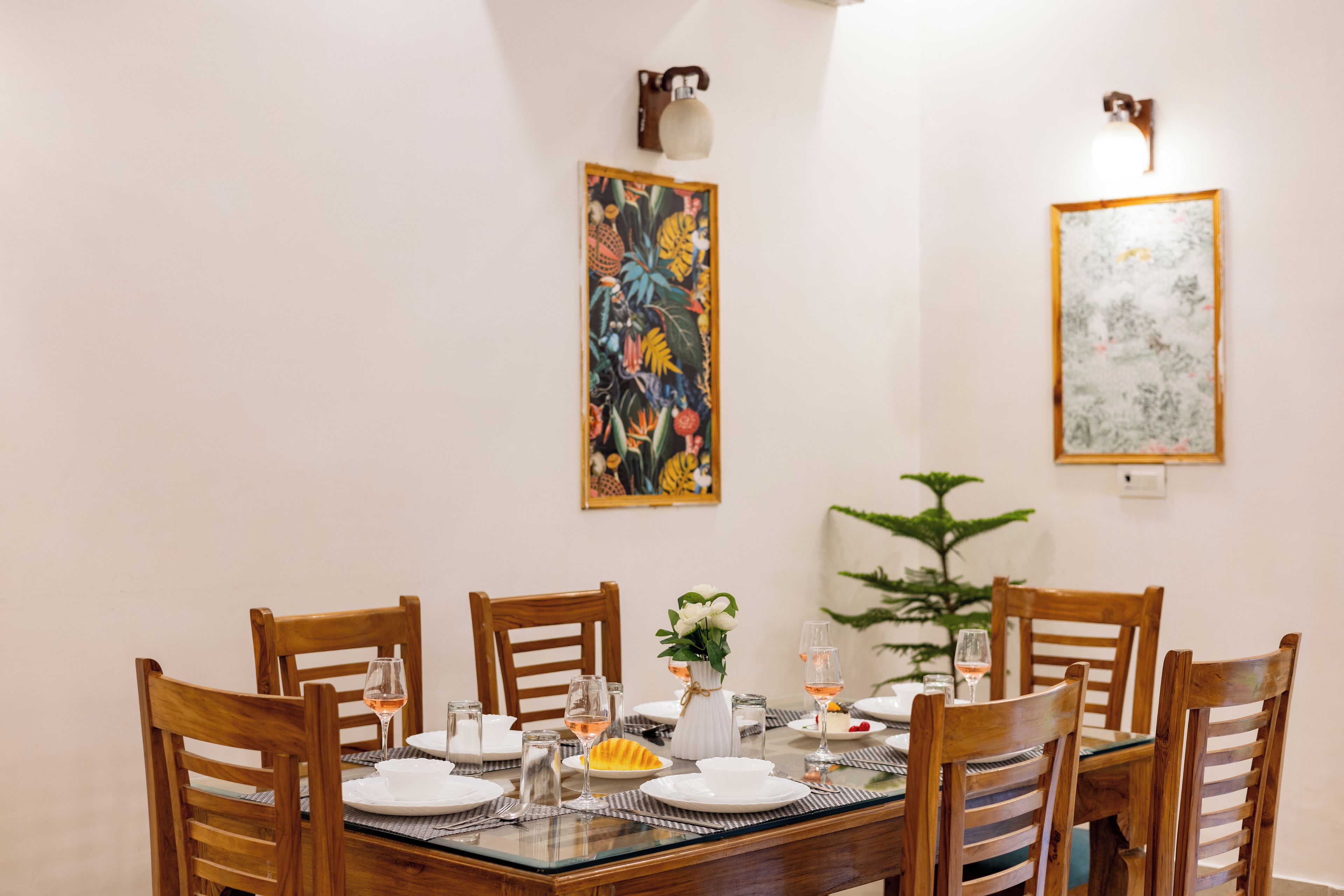 A dining area with a round table, wooden chairs, and wall-mounted light fixtures.