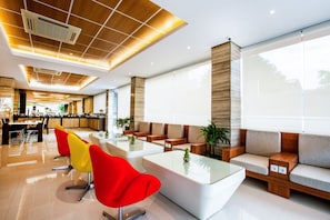 A modern hotel lobby with a reception desk, seating area, and large windows. - The Point Hotel Balikpapan (Balikpapan)