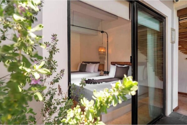 A bedroom with a bed, pillows, and a bedside table. - Suite con vista a la alberca - Paraíso caribeño (Playa del Carmen)
