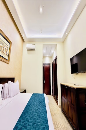 A hotel room with a bed, a television, an air conditioning unit, and a door leading to another room. - Bafana Pyramids Hotel & Spa (Giza)