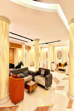 A spacious lobby with a modern design, featuring a sectional sofa, a coffee table, and a vibrant orange armchair. - Bafana Pyramids Hotel & Spa (Giza)