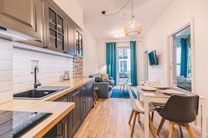 A compact hotel room with a kitchenette, a dining area, and a living space with a view to the outside.