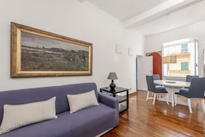 A living room with a sofa, a table, and a painting on the wall. - Bernini in Cavour - Monti District (Rome)