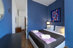 A bedroom with a bed, a bedside table, a lamp, and a wall art piece. - Bernini in Cavour - Monti District (Rome)