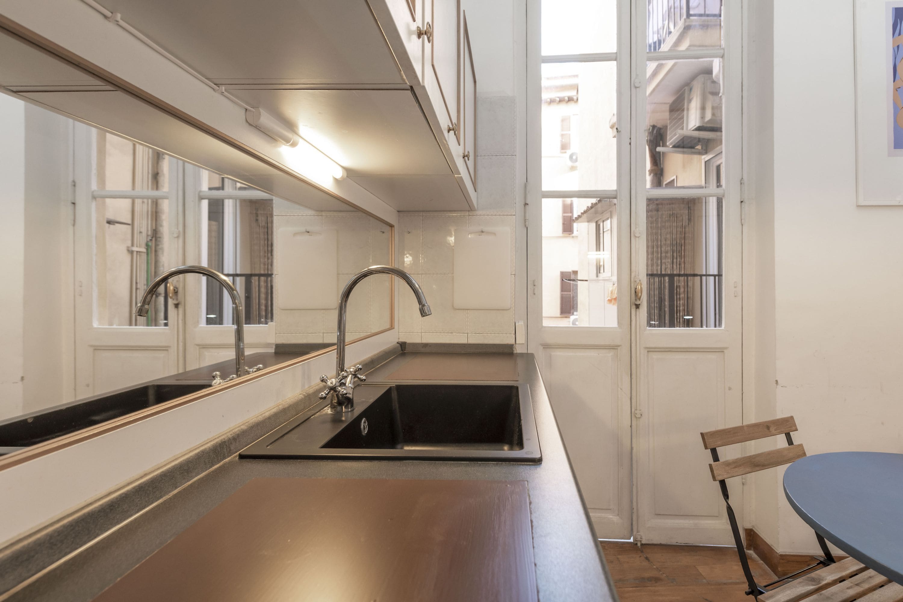 Une cuisine équipée d’un évier à deux bacs, d’un miroir et offrant une vue sur l’extérieur.