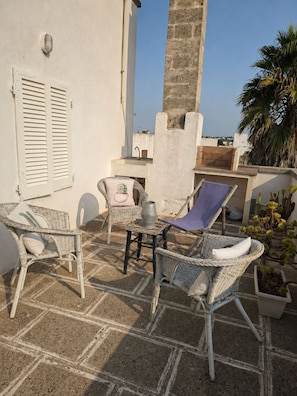 An outdoor patio with wicker furniture, a table, and potted plants. - An authentic Salento home with a private courtyard, in the heart of Salento (Giuliano Di Lecce)