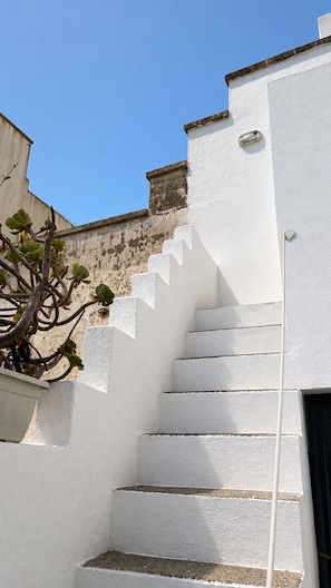 A white staircase leading to a door, with a plant on the left and a clear blue sky in the background. - An authentic Salento home with a private courtyard, in the heart of Salento (Giuliano Di Lecce)