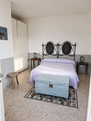 A bedroom with a bed, a chest of drawers, a small stool, and a nightstand with a lamp. - An authentic Salento home with a private courtyard, in the heart of Salento (Giuliano Di Lecce)