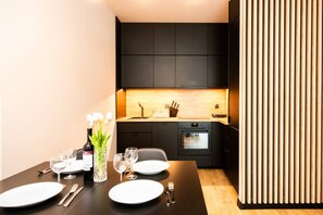 A modern kitchen with dark cabinets, a wooden countertop, and an oven. - Let's Sea Gąski by 2HomeRent (Gąski)