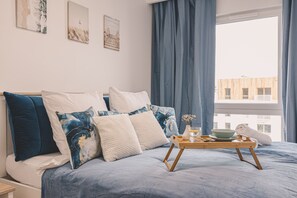 A bedroom with a bed, pillows, a tray with a bowl, a vase, and a towel. - Let's Sea Gąski by 2HomeRent (Gąski)