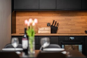 Une cuisine moderne avec un plan de travail en bois, un porte-couteaux noir et une petite horloge.