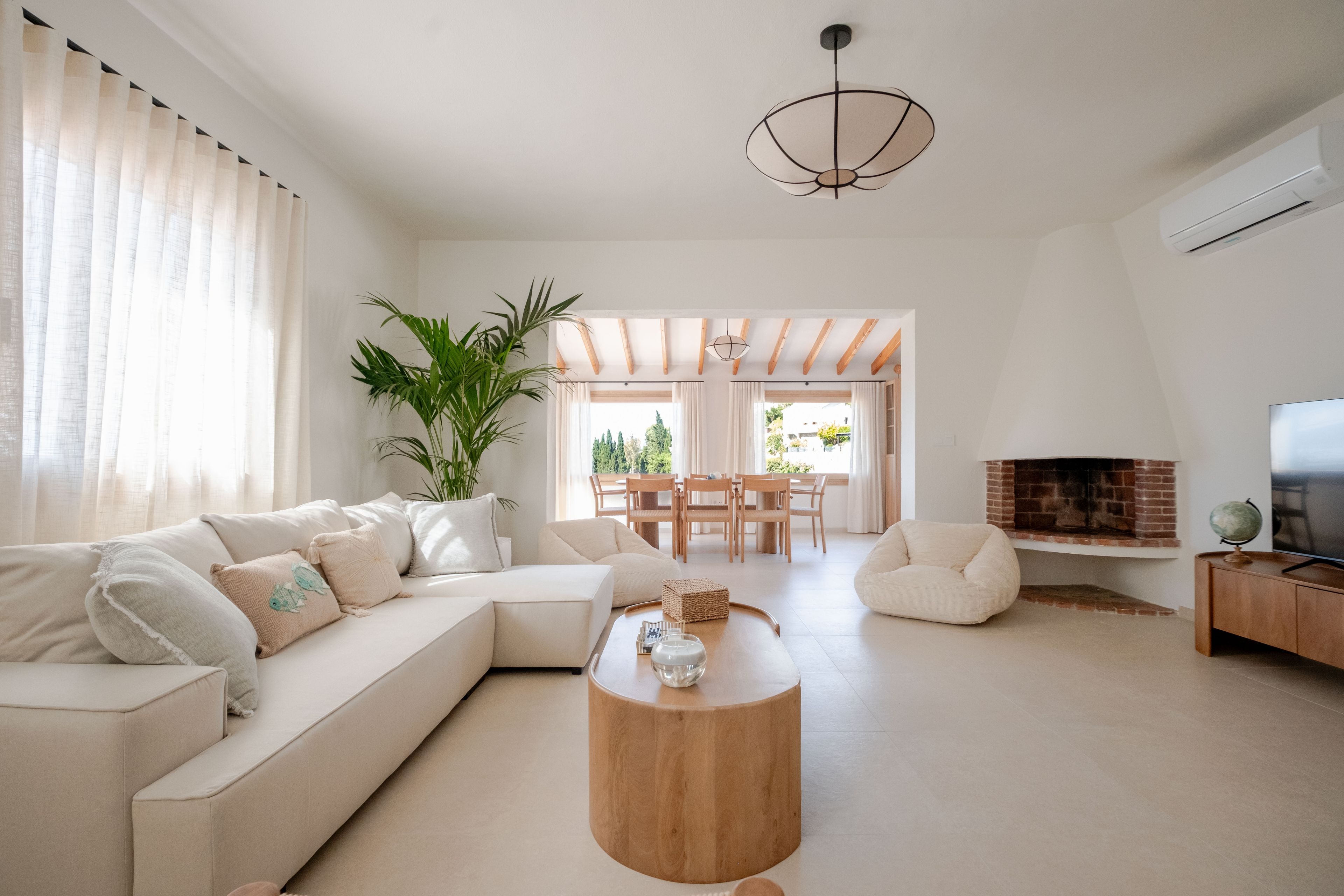Uma sala de estar moderna com um sofá modular, uma mesa de centro de madeira e uma TV sobre um suporte de madeira.