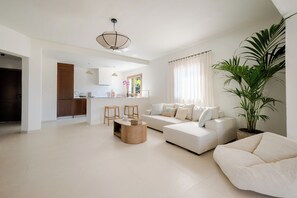 A modern living room with a sofa, a coffee table, and a large potted plant.