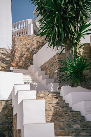 A set of white stairs leading up a stone wall, with a white railing on the upper landing.