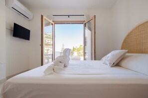Une chambre d’hôtel avec un lit, un téléviseur fixé au mur et une vue sur l’extérieur.