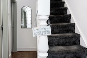 A staircase with a sign that reads 'Welcome, Leave your worries and your shoes at the door.' - Modern 6BR House with free parking (Manchester)