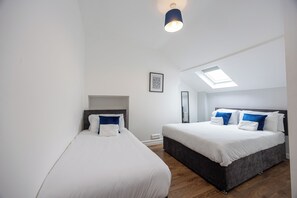 Un dormitorio moderno con dos camas, un tragaluz y un aplique de techo.