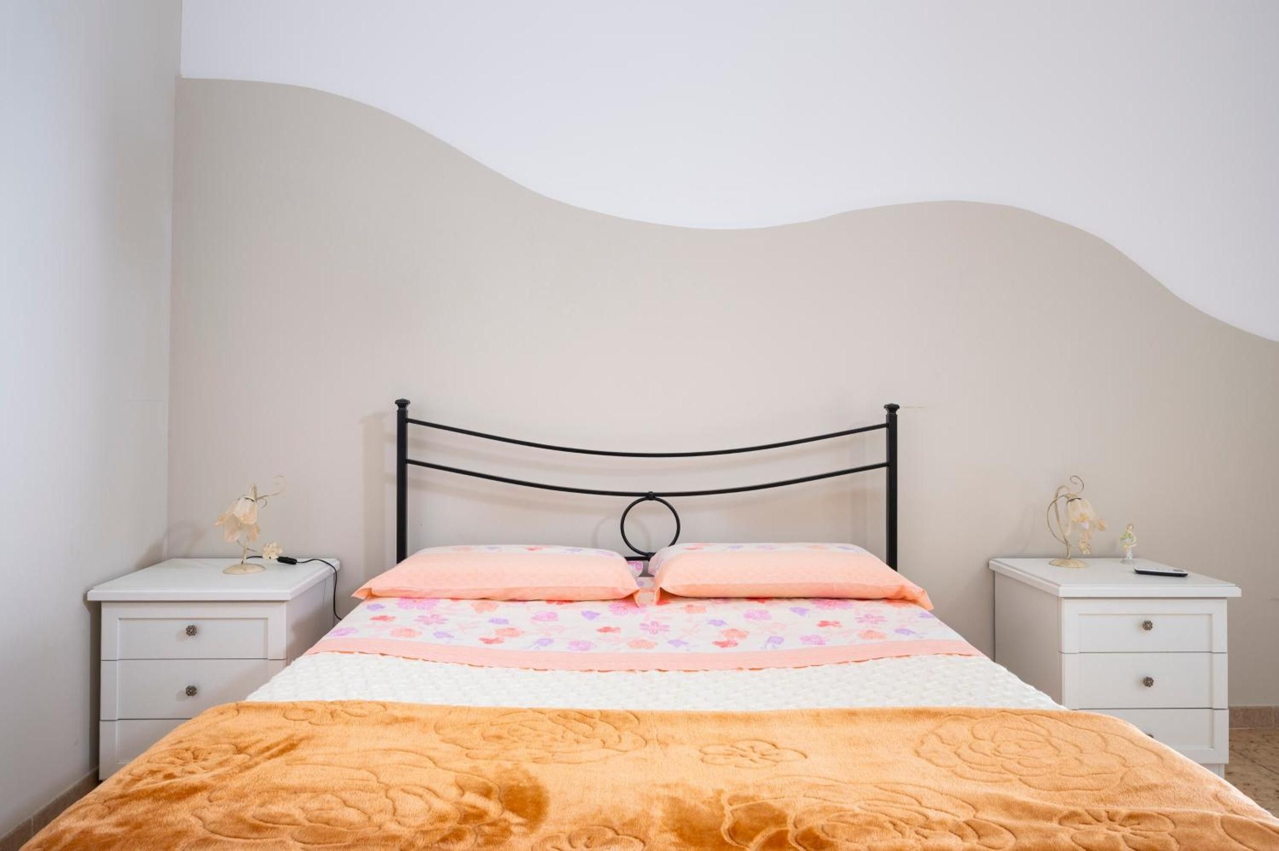 A bed with a headboard, two bedside tables, and a wall with a wavy design.