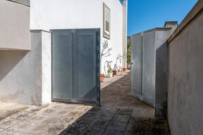 A narrow alleyway with a closed metal gate, potted plants, and a bicycle. - Apartment 'Db Apartments' with Wi-Fi and Air Conditioning (Giurdignano)