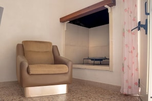 Un fauteuil en cuir marron, avec un coussin à carreaux, se trouve dans une pièce dont le sol est recouvert de carreaux.