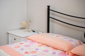 Une chambre à coucher avec un lit, une table de chevet et une lampe.